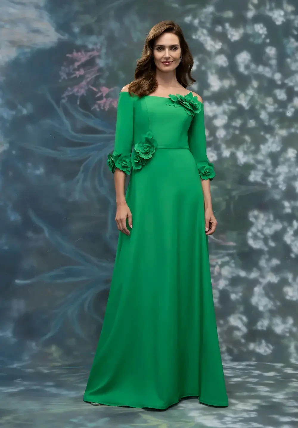 A woman in a long, off-shoulder green dress with floral embellishments.