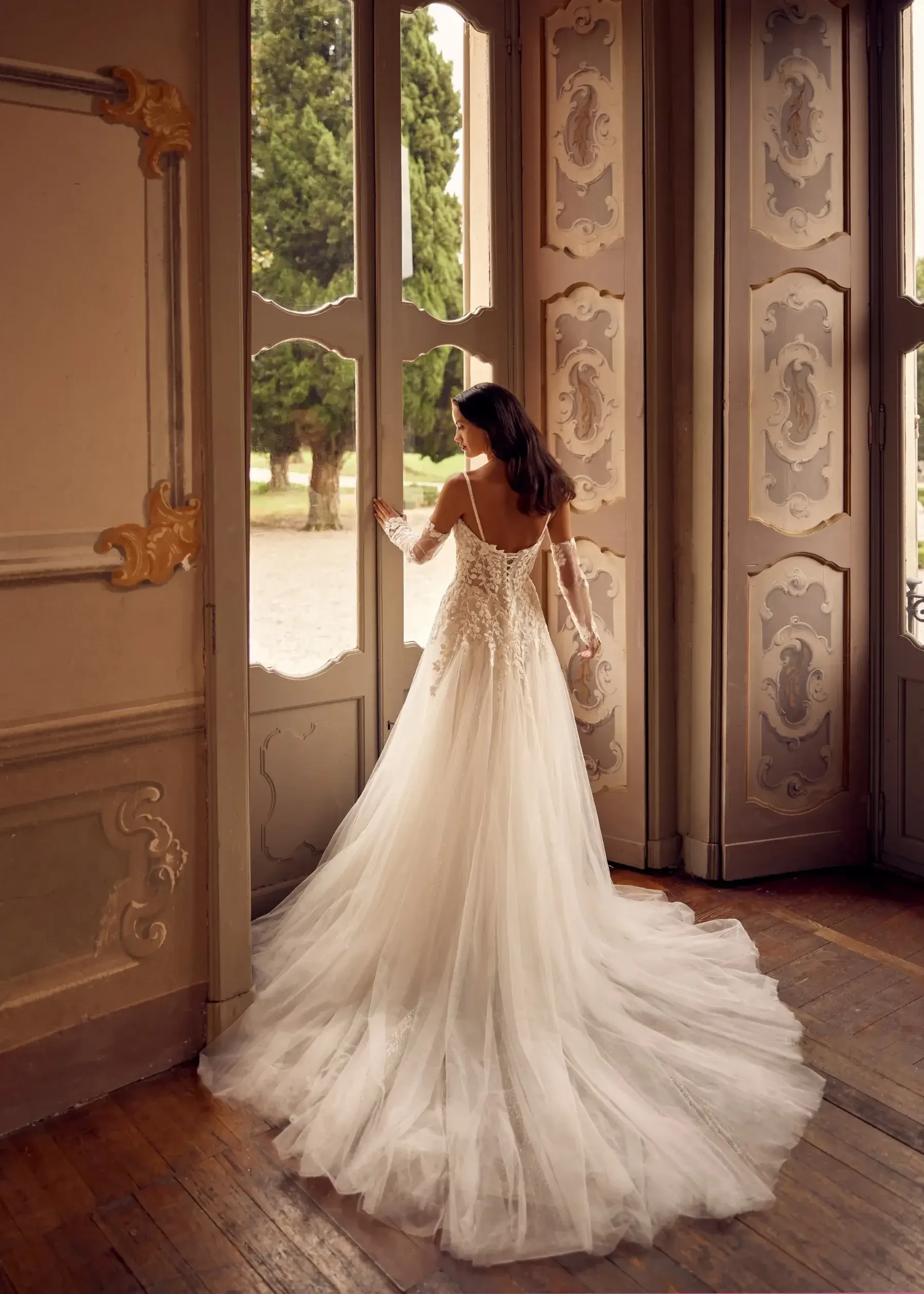 model is wearing a long sleeve lace ball gown