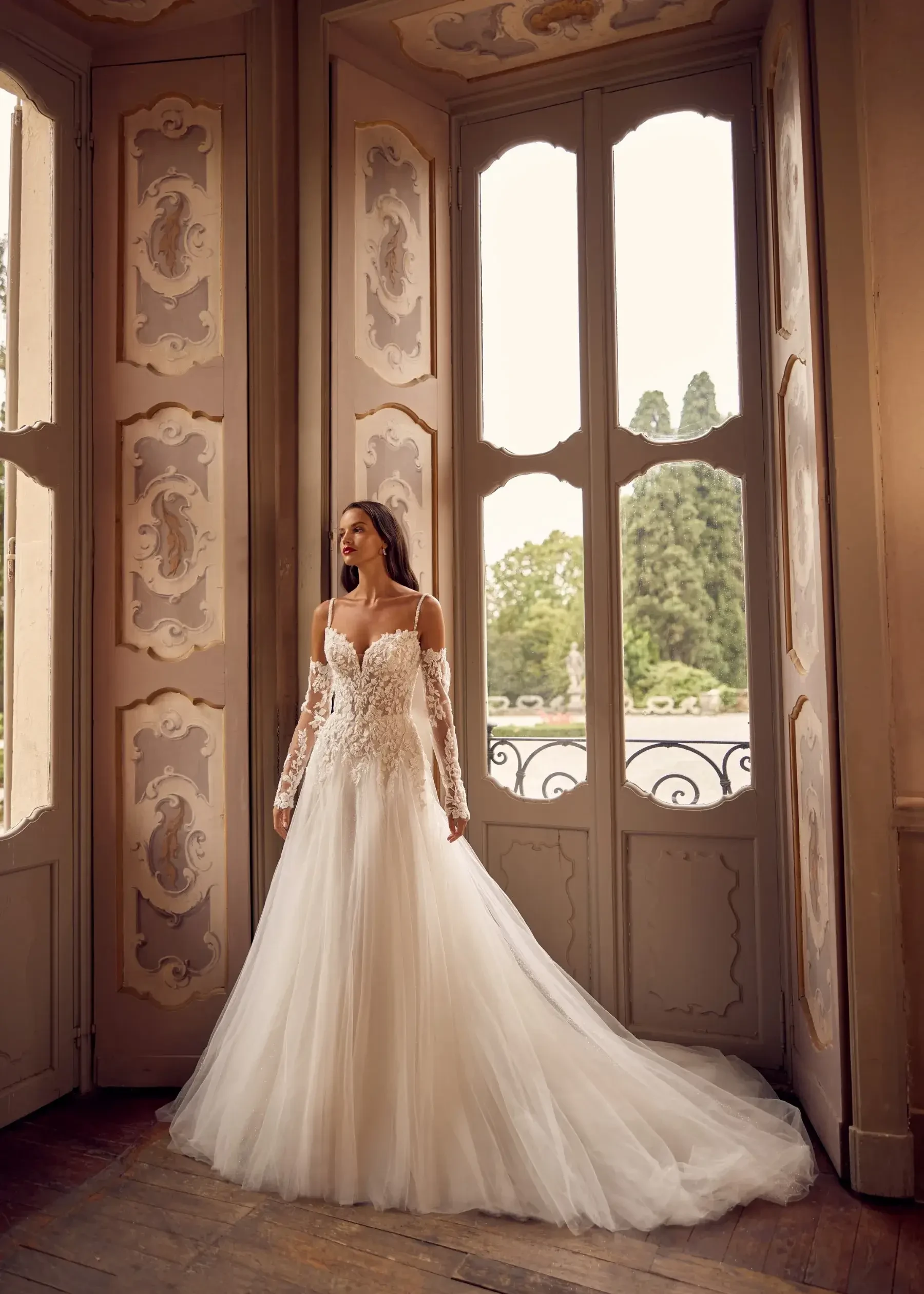 model is wearing a long sleeve lace ball gown